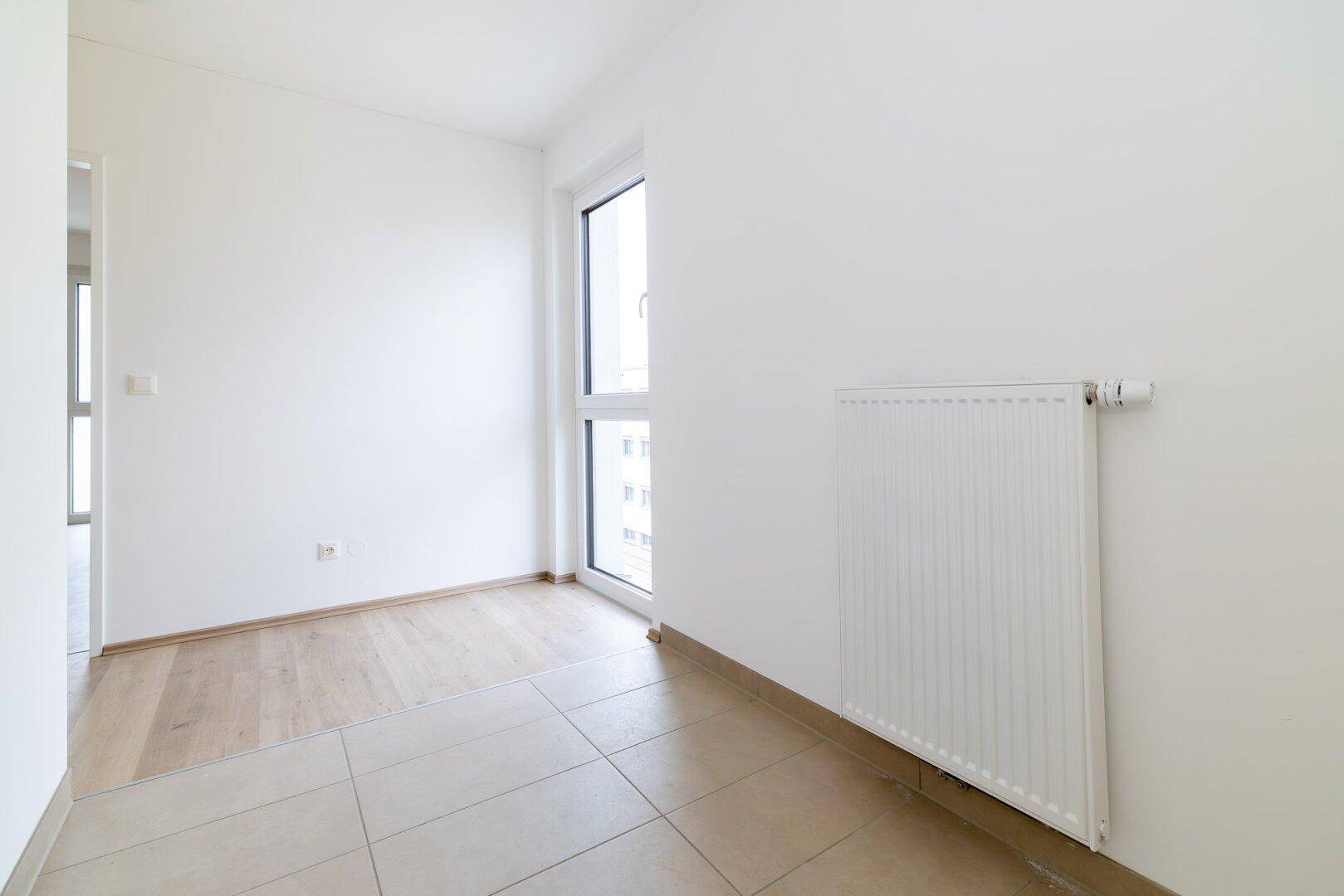 Heller Flurbereich mit Fliesenboden und Fenster, der zu weiteren Räumen führt.