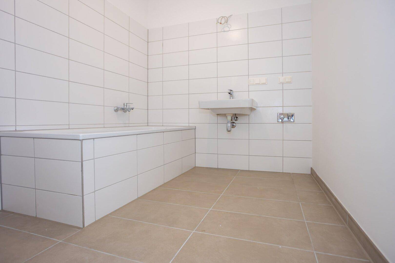 Modernes Badezimmer mit weißen Fliesen, Badewanne und einem Waschbecken.