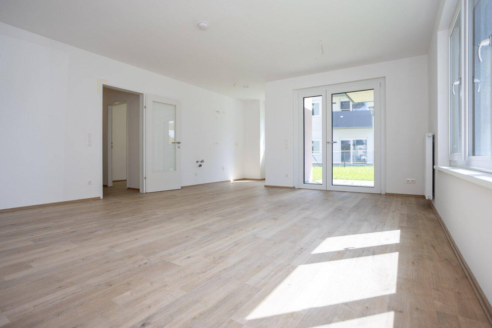 Heller, geräumiger Wohnbereich mit Laminatboden und großen Fenstern zum Garten.