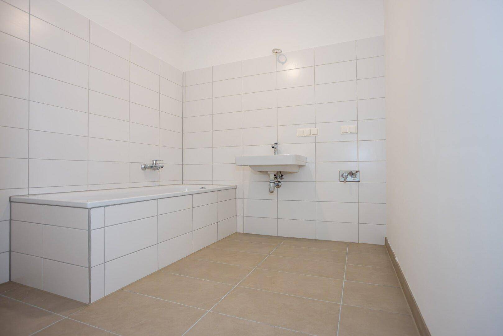 Modernes Badezimmer mit weiß gefliesten Wänden, Badewanne und Waschbecken.
