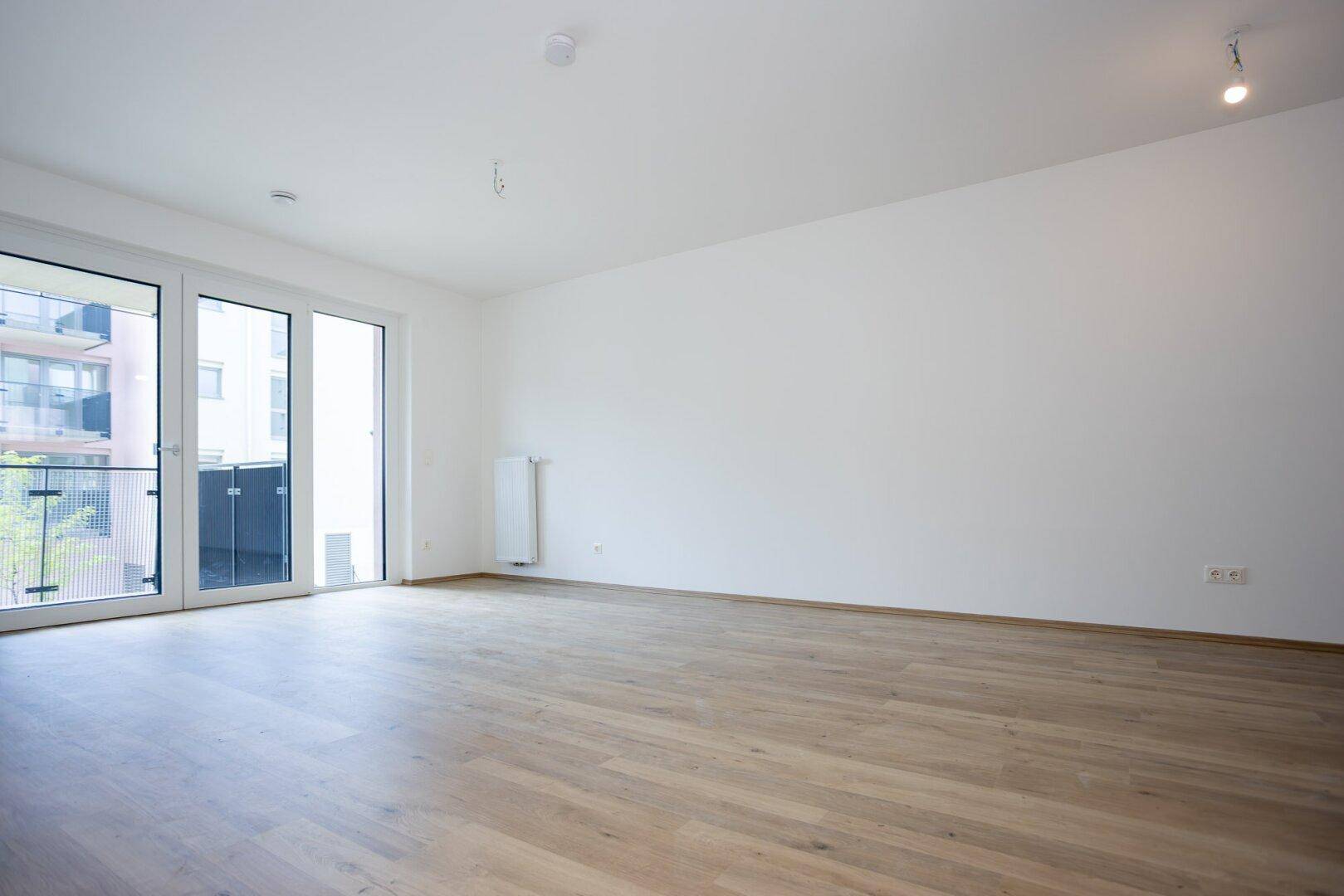 Helles und geräumiges Zimmer mit Laminatboden und großem Balkonzugang, viel Tageslicht.