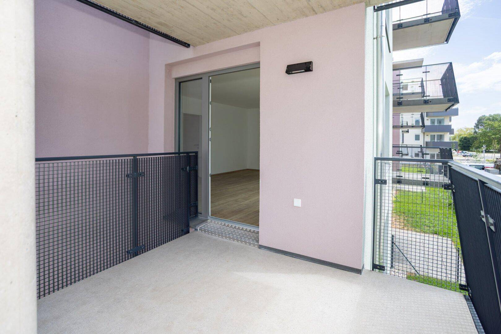 Geräumiger Balkon mit Metallgeländer und Zugang zu einem hellen Innenraum.