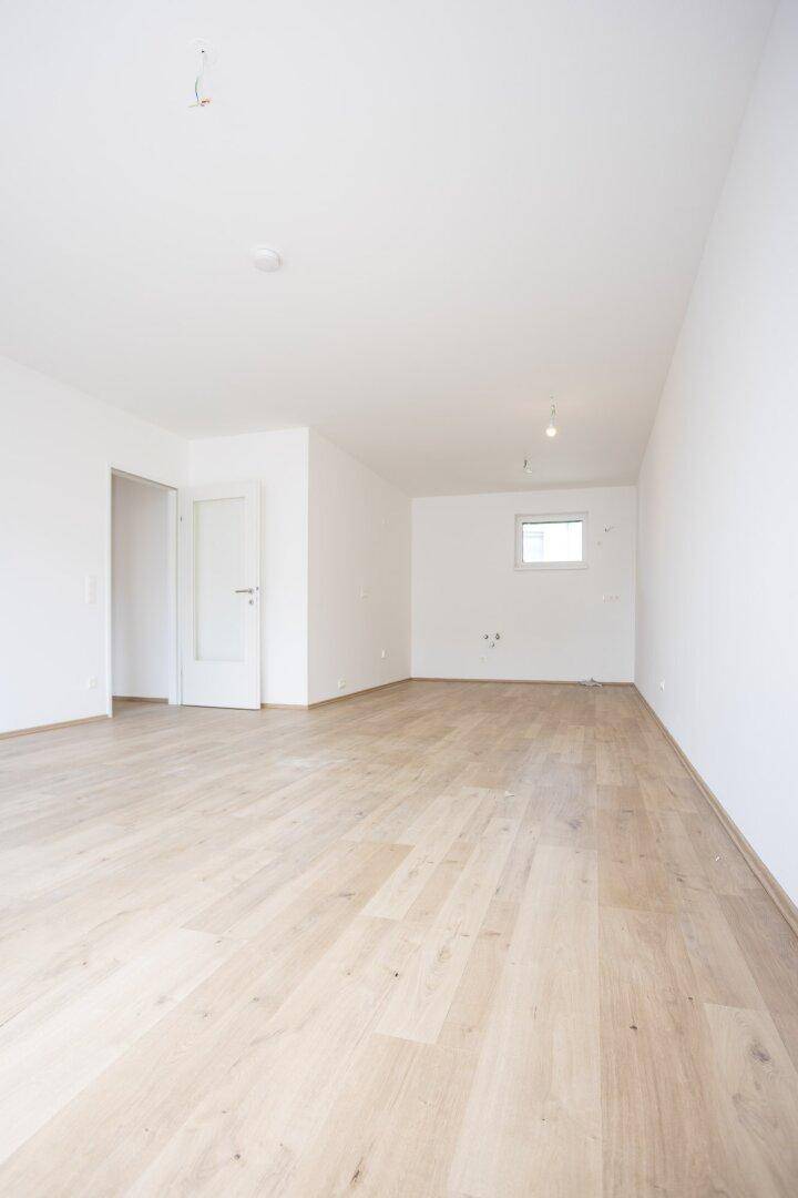 Heller, leerer Raum mit Holzboden und weißen Wänden, ideal für individuelle Nutzung.