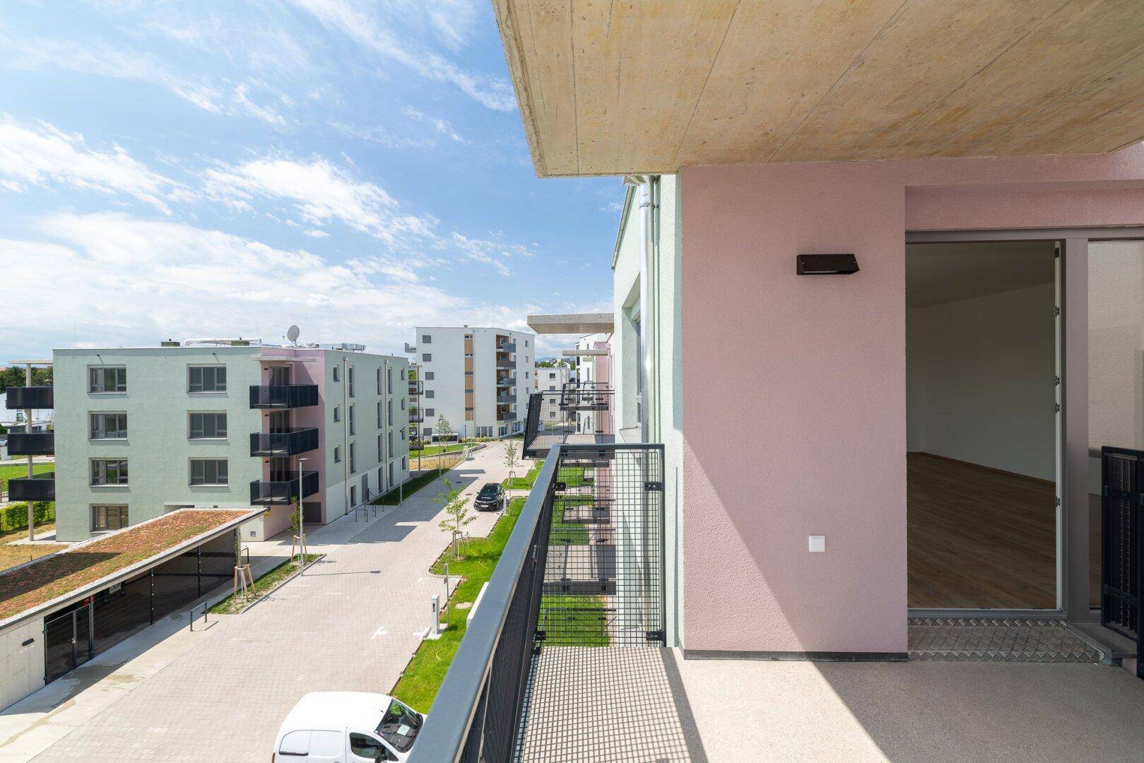 Balkon mit Blick auf die moderne Wohnanlage und die umliegenden Gebäude unter blauem Himmel.