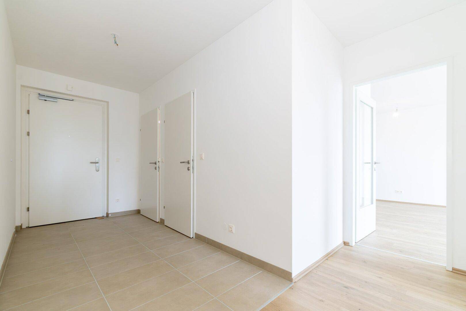 Geräumiger, heller Flur mit Fliesenboden und mehreren weißen Türen.