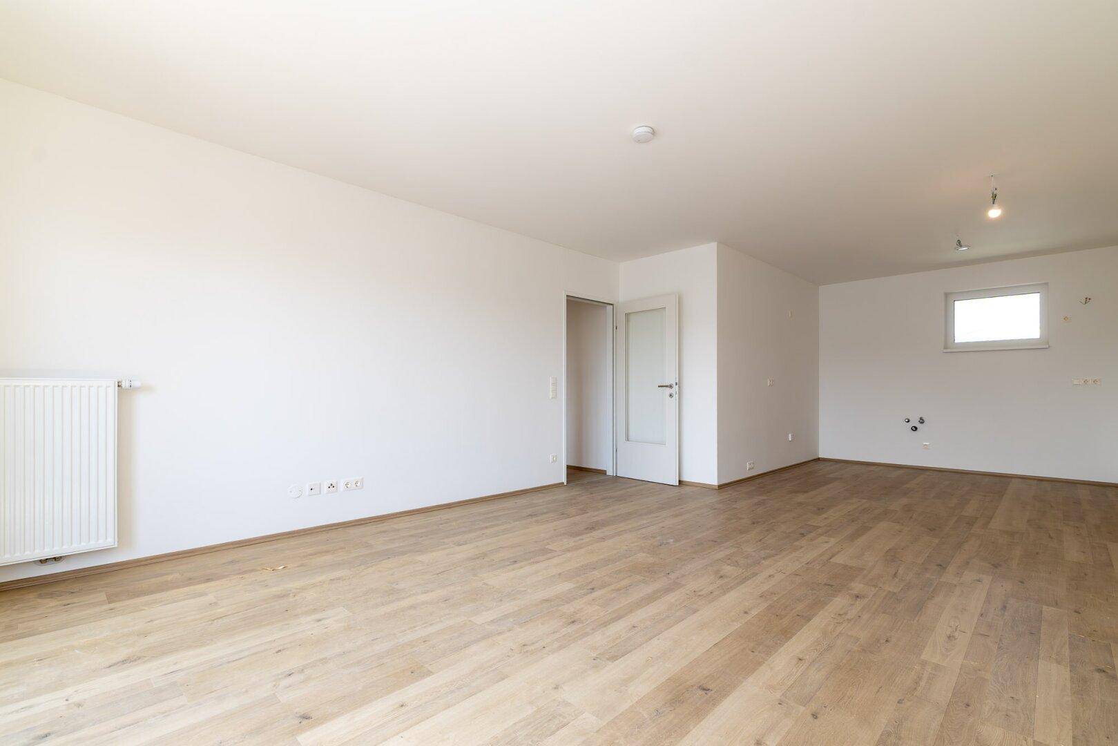 Heller Wohnbereich mit Laminatboden und viel Platz für individuelle Gestaltungsmöglichkeiten.