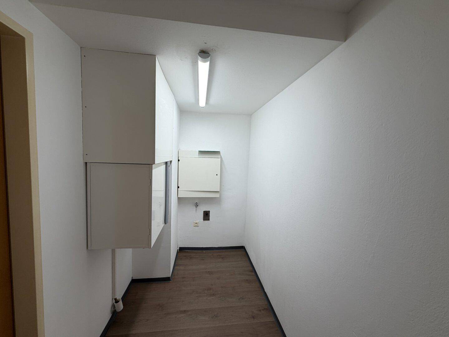 Funktionaler Hauswirtschaftsraum mit weißen Wänden und dunklem Boden, ideal für Lagerung.