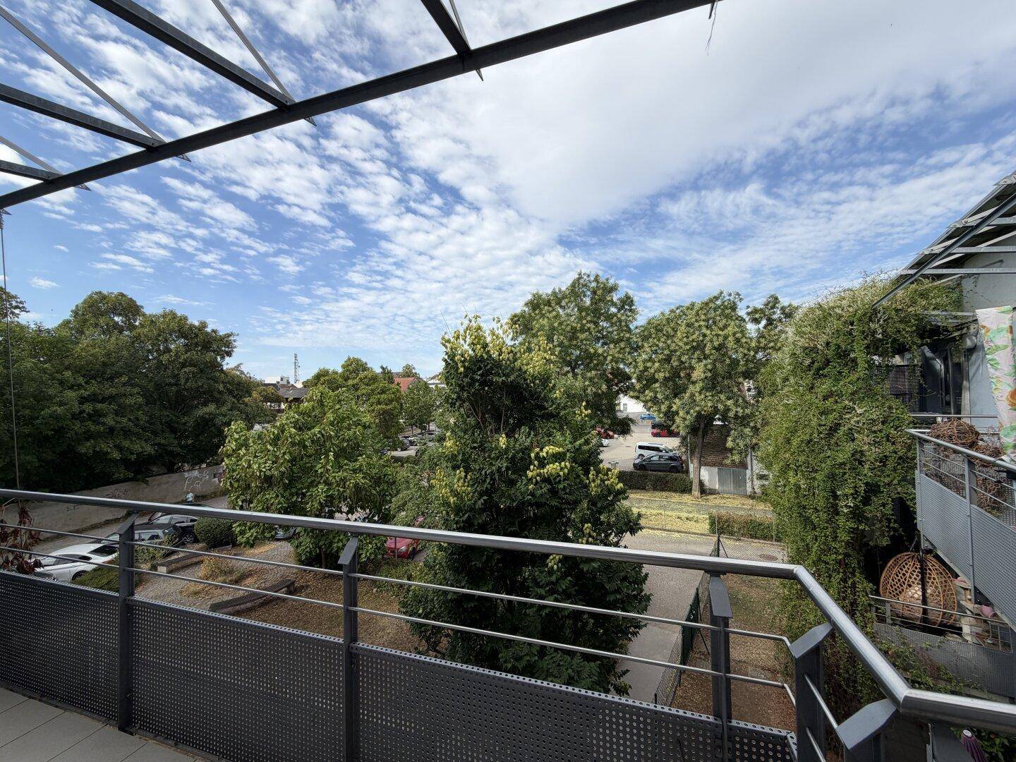 Geräumiger Balkon mit Metallgeländer und Blick auf die grüne Umgebung und Nachbarschaft.