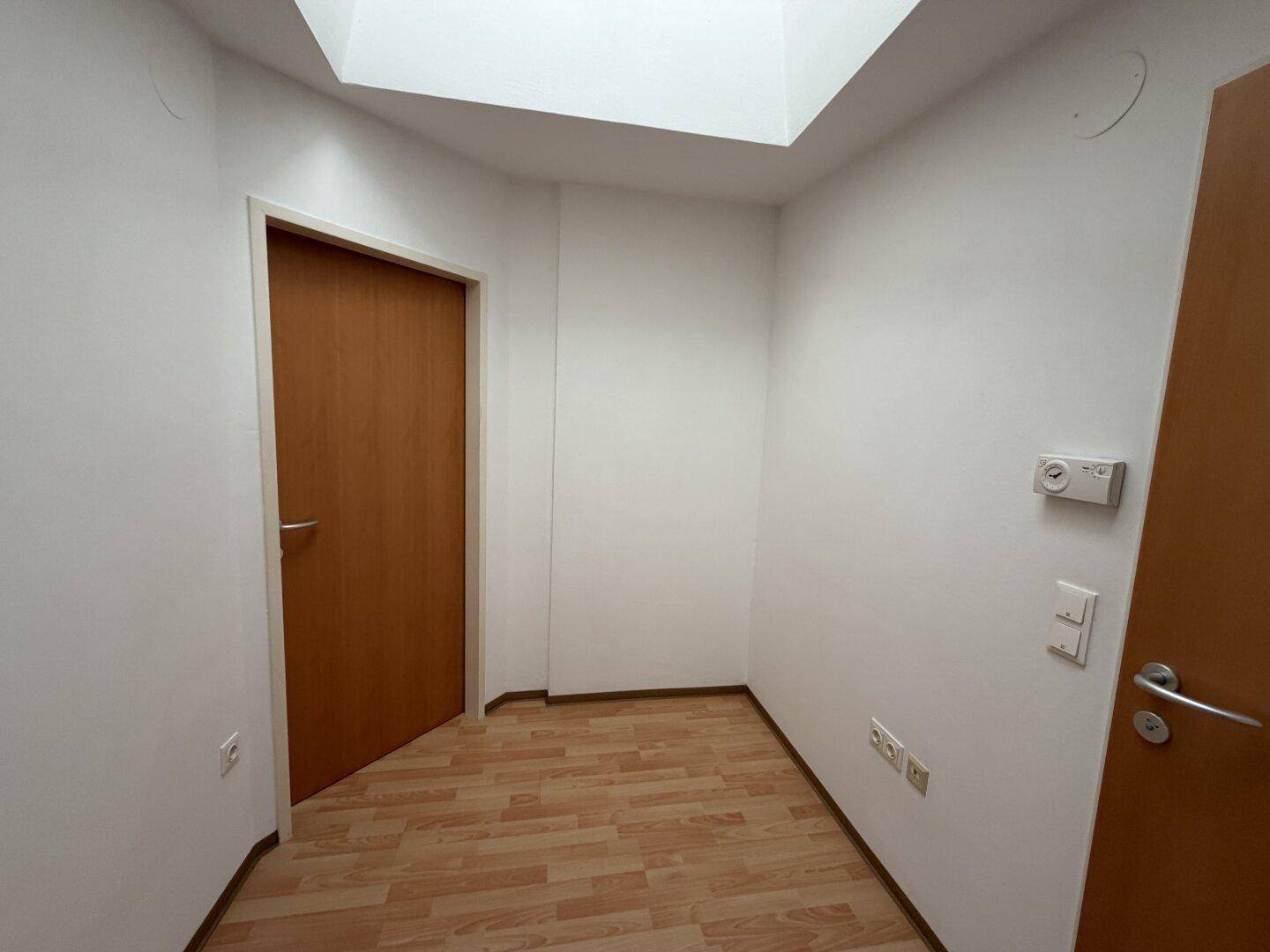 Heller Eingangsbereich mit Laminatboden und Oberlicht, verbindet verschiedene Wohnbereiche.