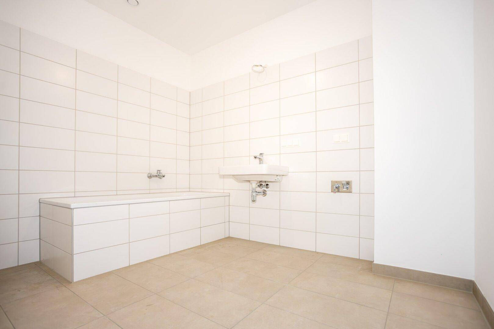 Modernes Badezimmer mit weißen Fliesen, Badewanne und Waschbecken.
