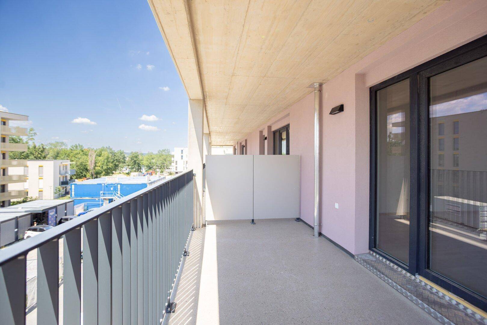 Langer Balkon mit moderner Brüstung und Blick auf die Umgebung.