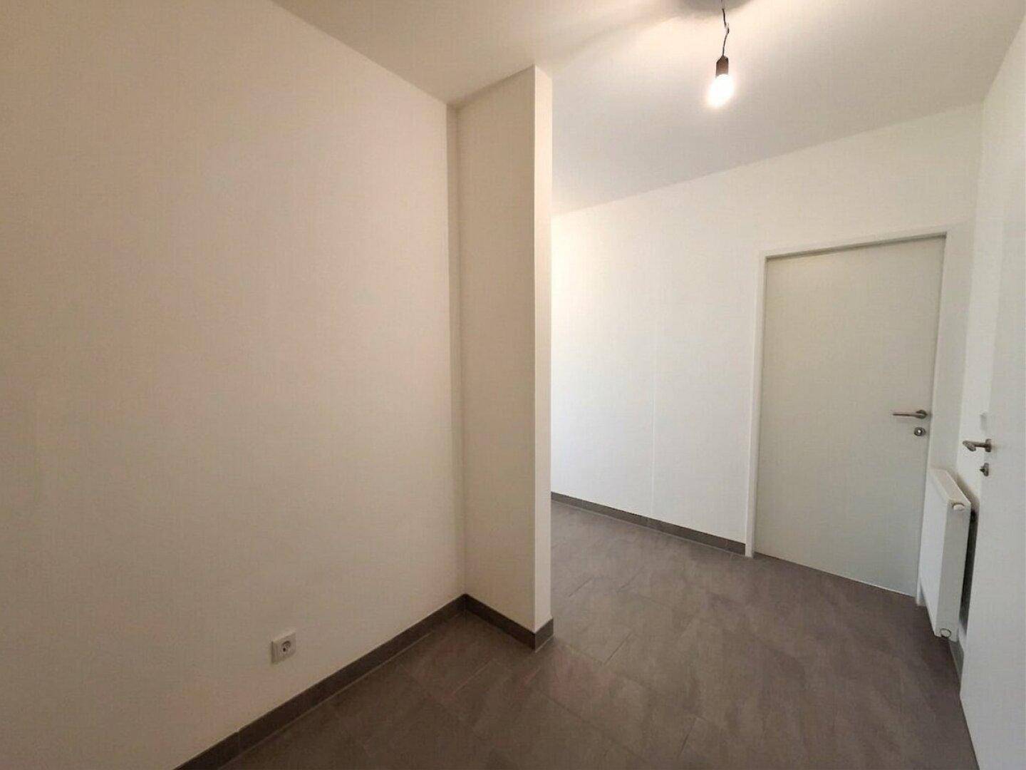 Schlichter Flur mit Fliesenboden und weißen Wänden, der die einzelnen Wohnbereiche miteinander verbindet.