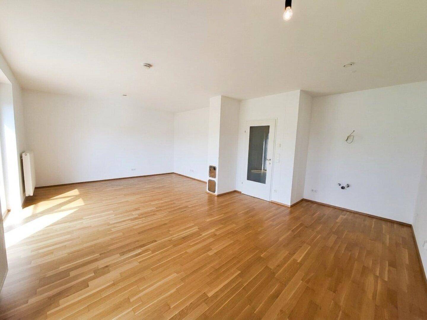 Großzügiges Wohnzimmer mit Parkettboden und viel Tageslicht, ideal für offene Wohnkonzepte.