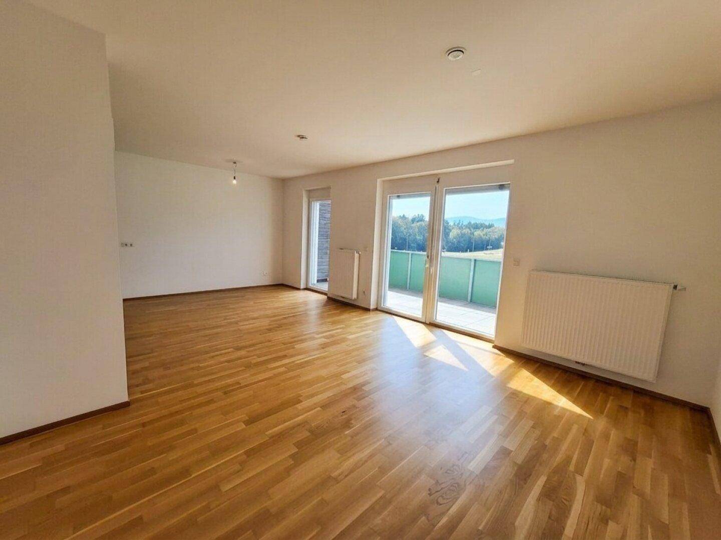 Lichtdurchflutetes Wohnzimmer mit Eichenparkett und direktem Zugang zu einem sonnigen Balkon.