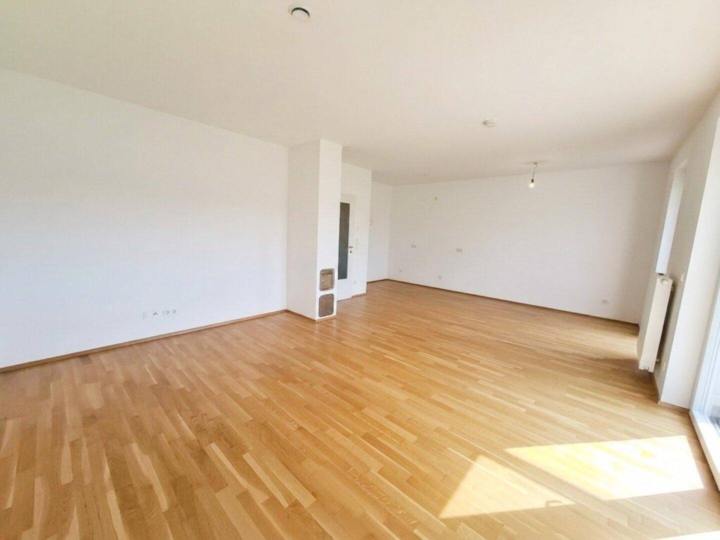 Geräumiges Wohnzimmer mit hellem Parkettboden und weiß gestrichenen Wänden, bereit zur individuellen Gestaltung.