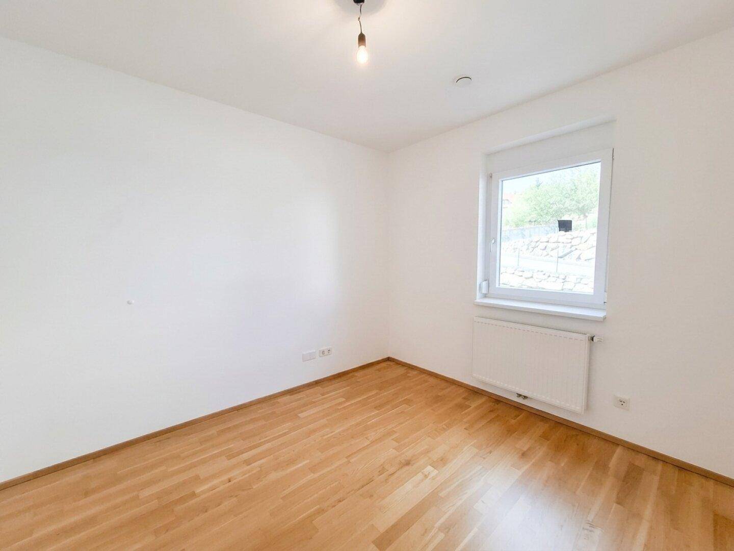 Geräumiges Zimmer mit Parkettboden und einem Fenster, das eine angenehme Wohnatmosphäre schafft.