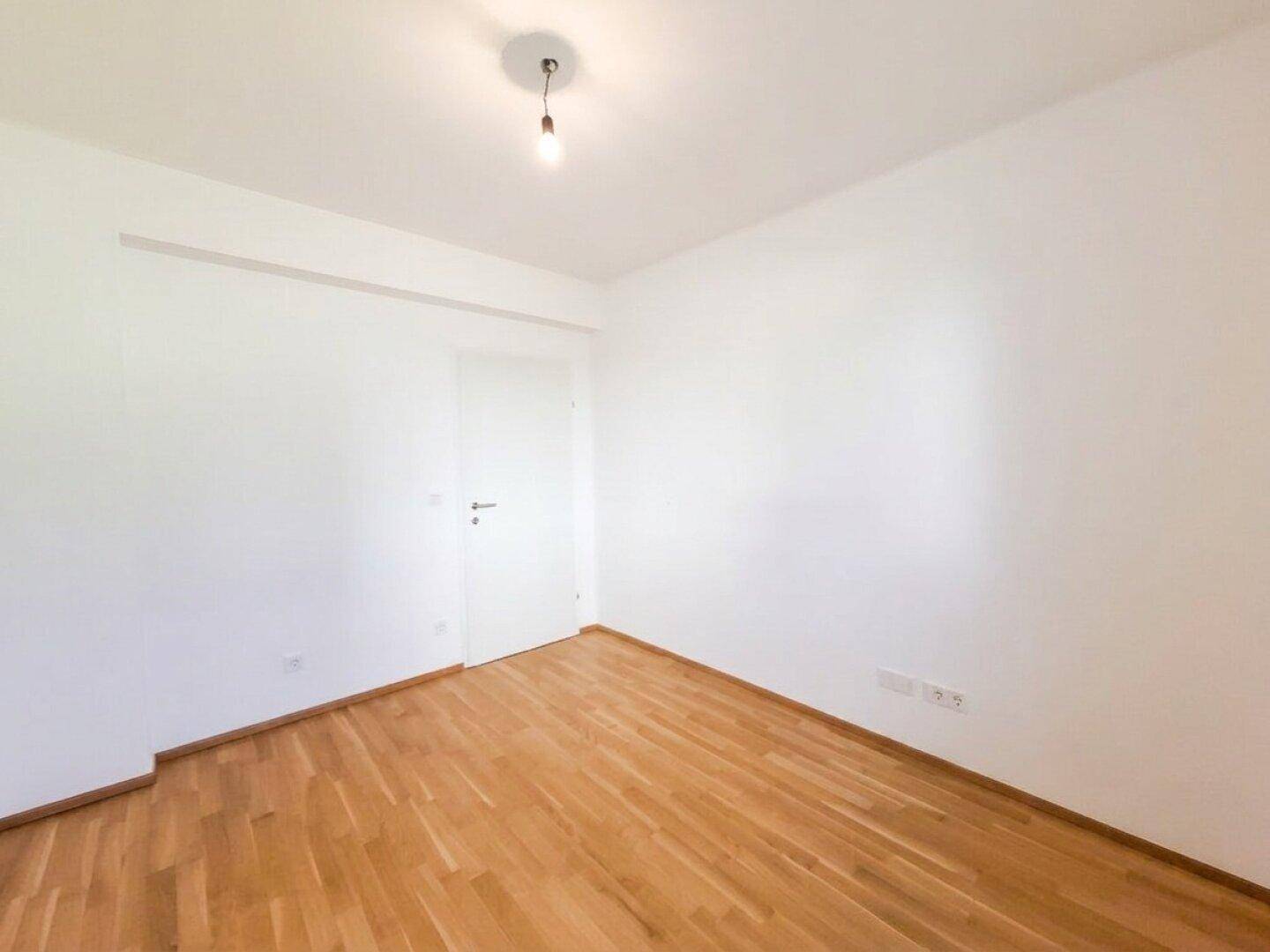 Neutral gestaltetes Zimmer mit Parkettboden und weißen Wänden, ideal für vielfältige Nutzungsmöglichkeiten.
