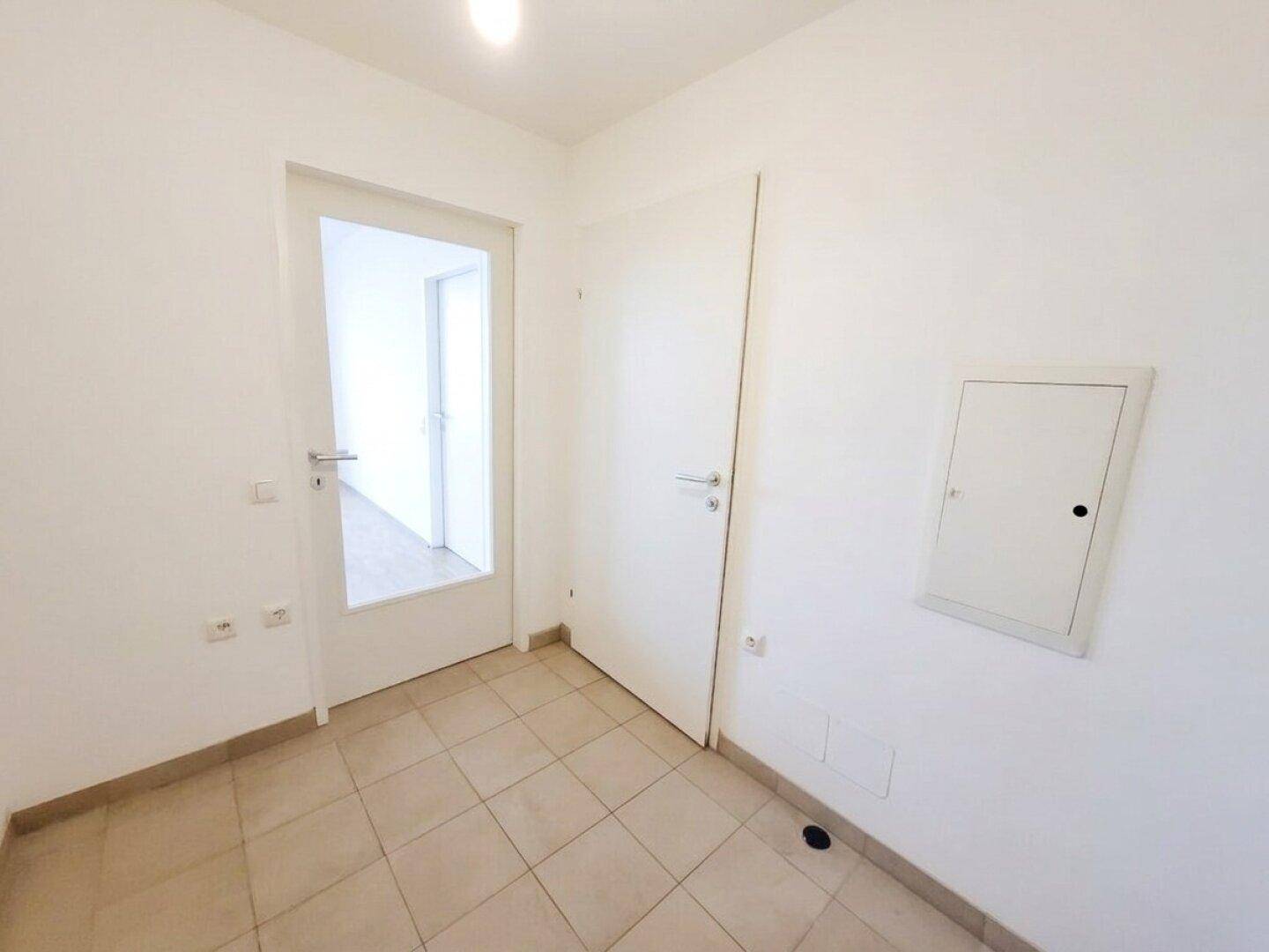 Heller Flur mit Fliesenboden und mehreren Türen, die zu den angrenzenden Räumen führen.