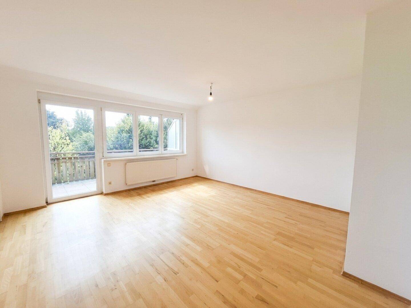 Lichtdurchfluteter Raum mit Parkettboden und direktem Zugang zum Außenbereich.