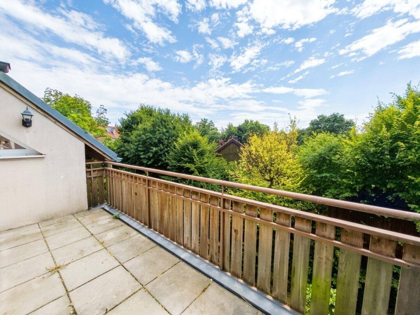 Heller Balkon mit Holzgeländer und weitem Blick auf die umliegende Natur.