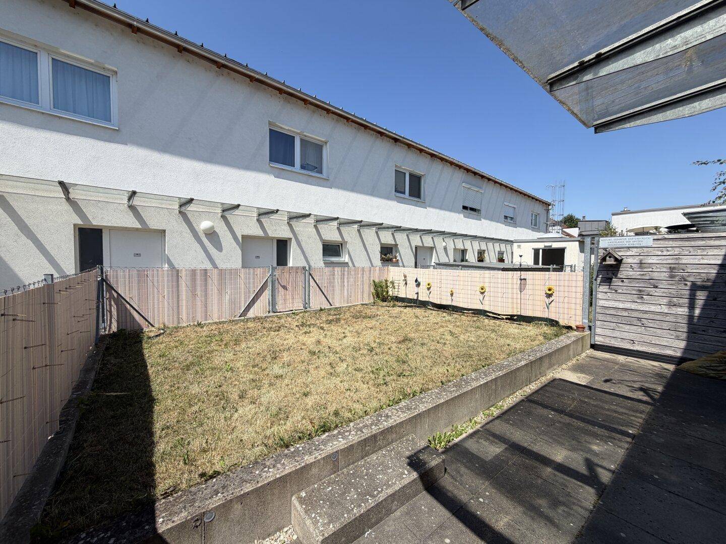 Kleiner privater Gartenbereich mit Rasenfläche und Holzumzäunung hinter dem Gebäude.