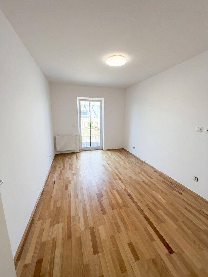 Helles Schlafzimmer mit Parkettboden und direktem Zugang zu einem Außenbereich.