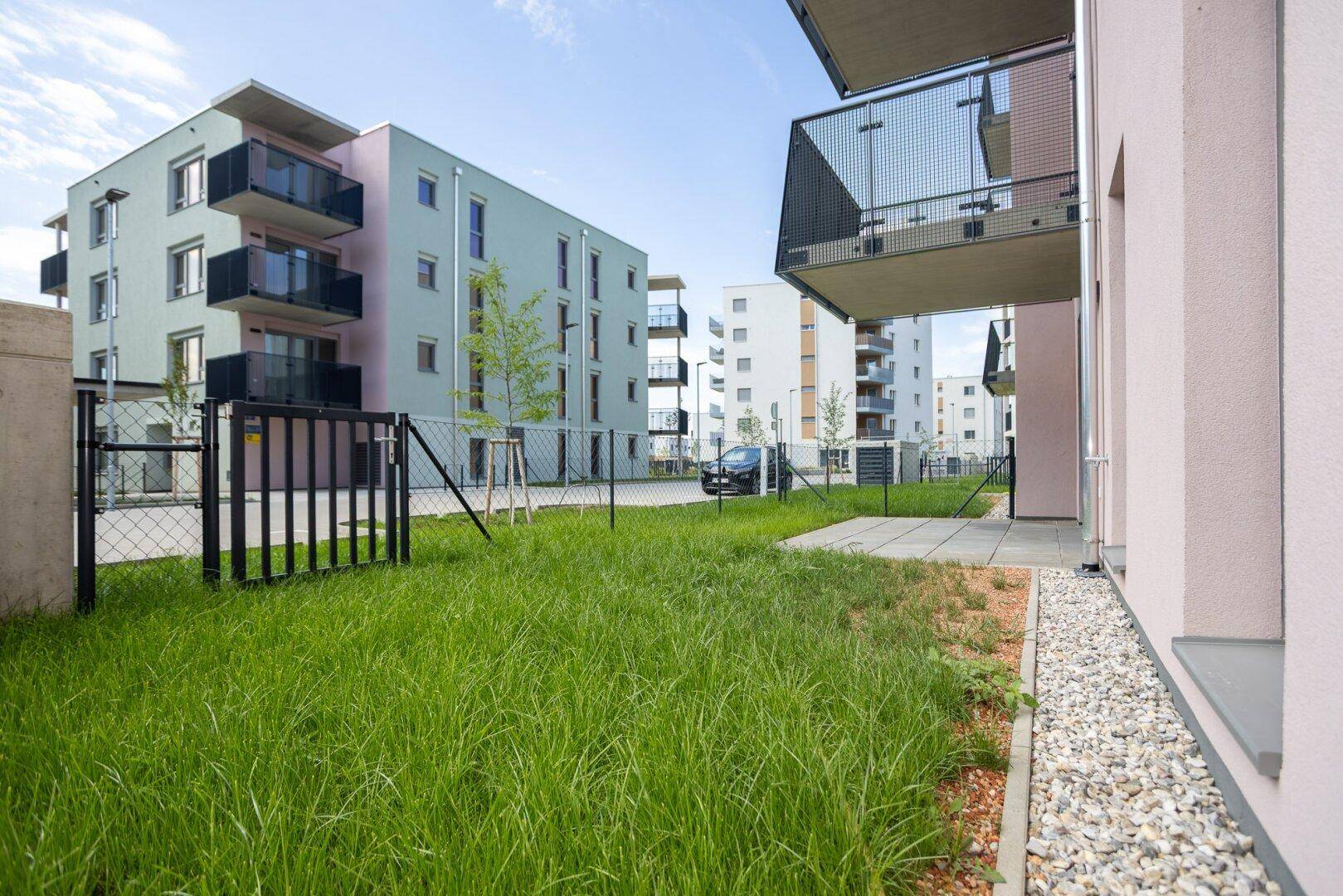 Außenansicht eines modernen Wohnkomplexes mit Grünflächen und Balkonen.