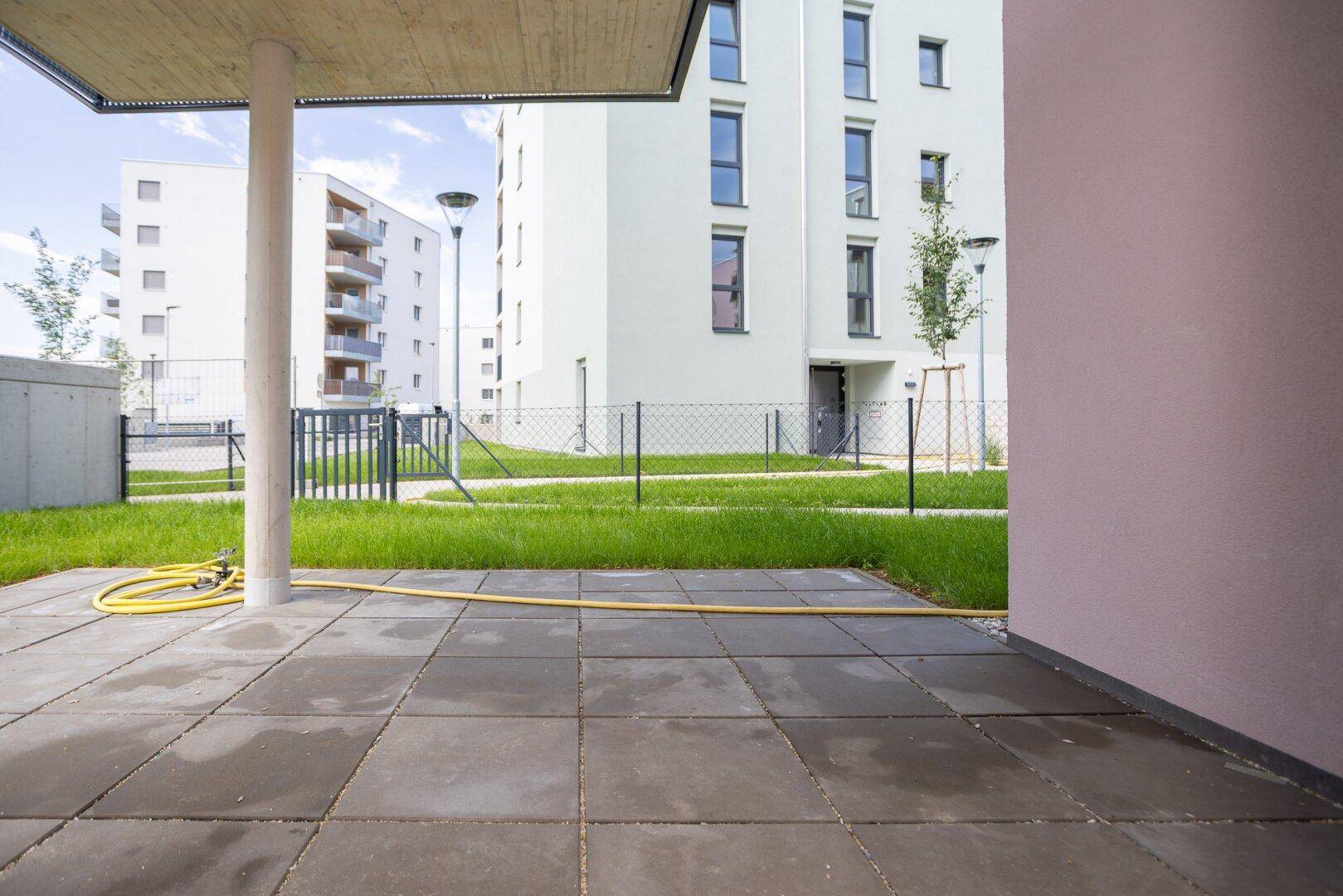 Gepflasterte Terrasse im Erdgeschoss mit Blick auf die umliegenden Neubauten.