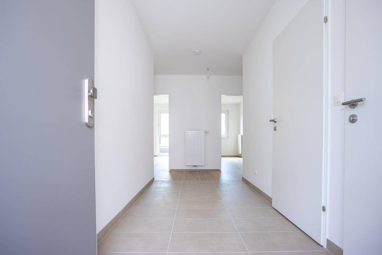 Heller Eingangsbereich mit Fliesenboden und Zugang zu verschiedenen Räumen der Wohnung.
