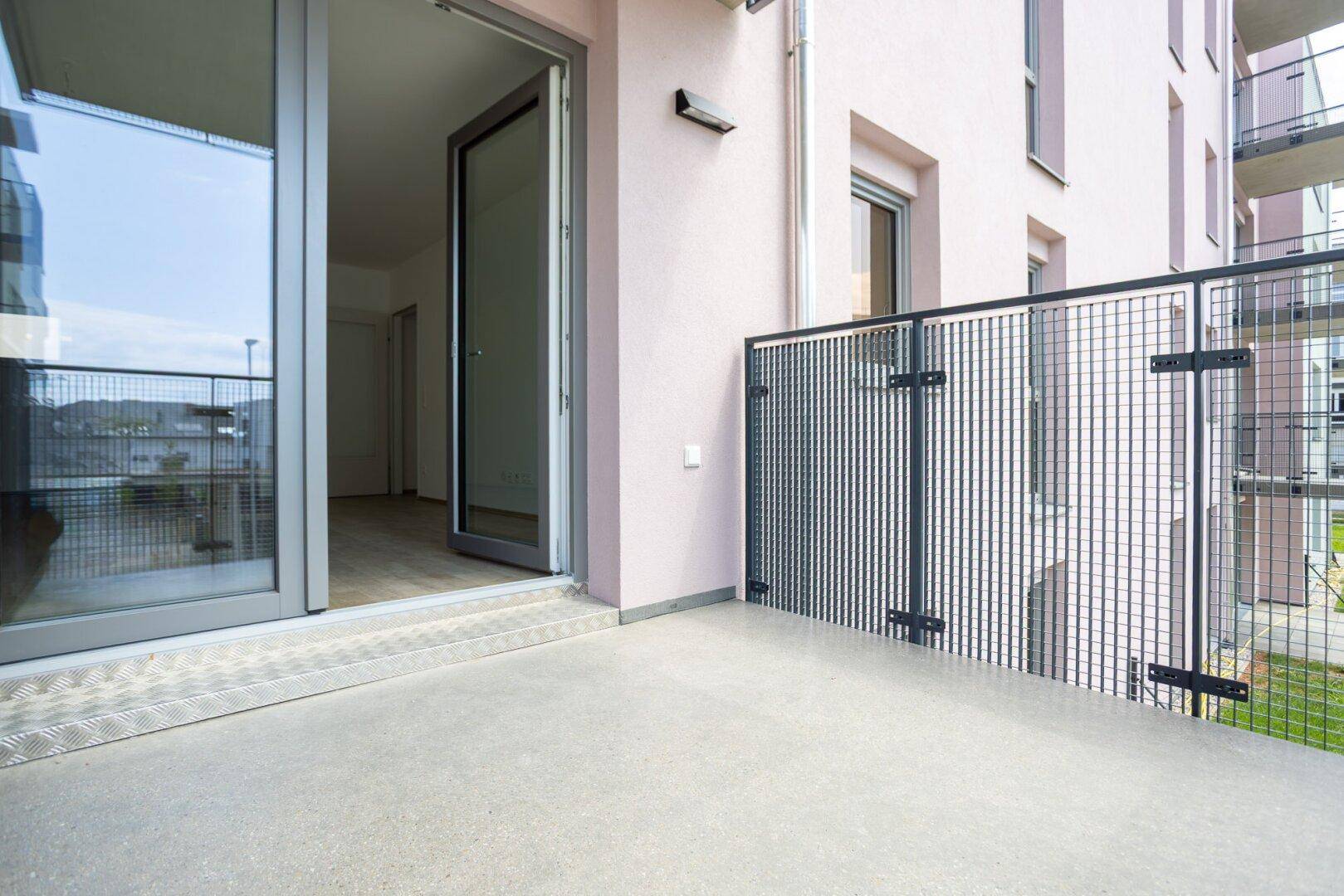 Kleiner Balkon mit Betonboden und Metallgeländer, zugänglich vom Innenraum.