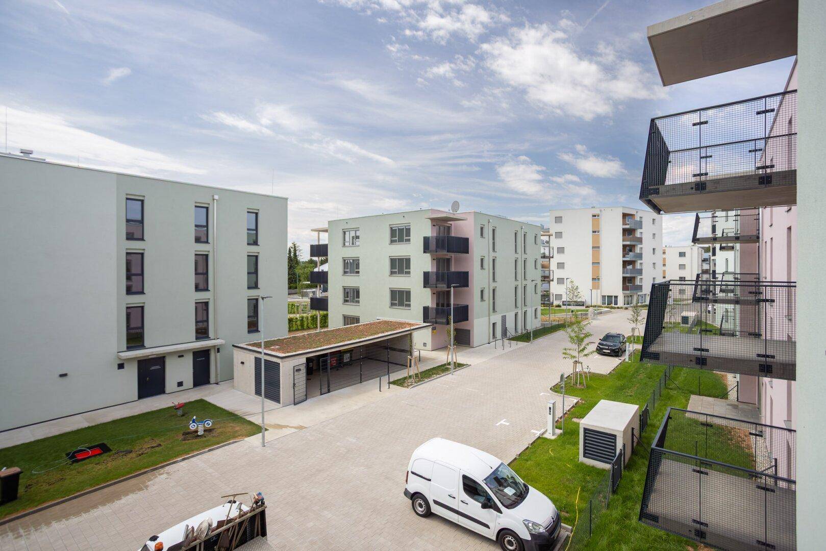 Moderne Wohnanlage mit mehreren Gebäuden, Grünflächen und Parkmöglichkeiten.