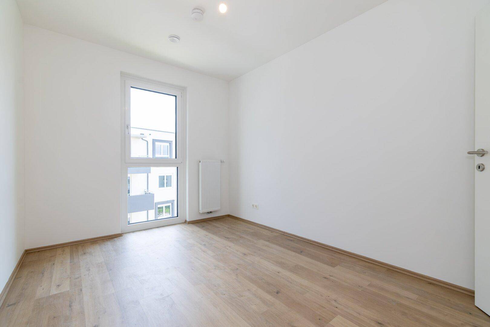 Geräumiges Zimmer mit hellem Laminatboden und Fenster, das viel natürliches Licht hereinlässt.