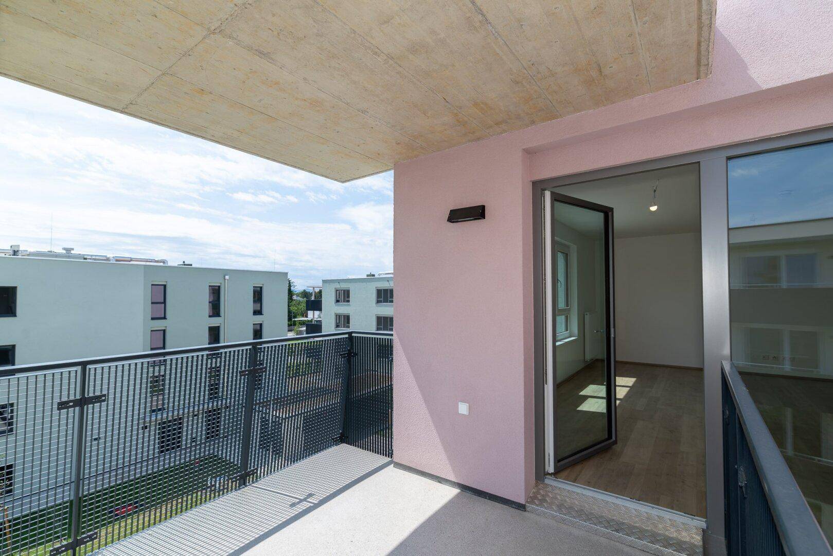 Moderner Balkon mit Blick auf die umliegenden Wohngebäude und die grüne Umgebung der Siedlung.
