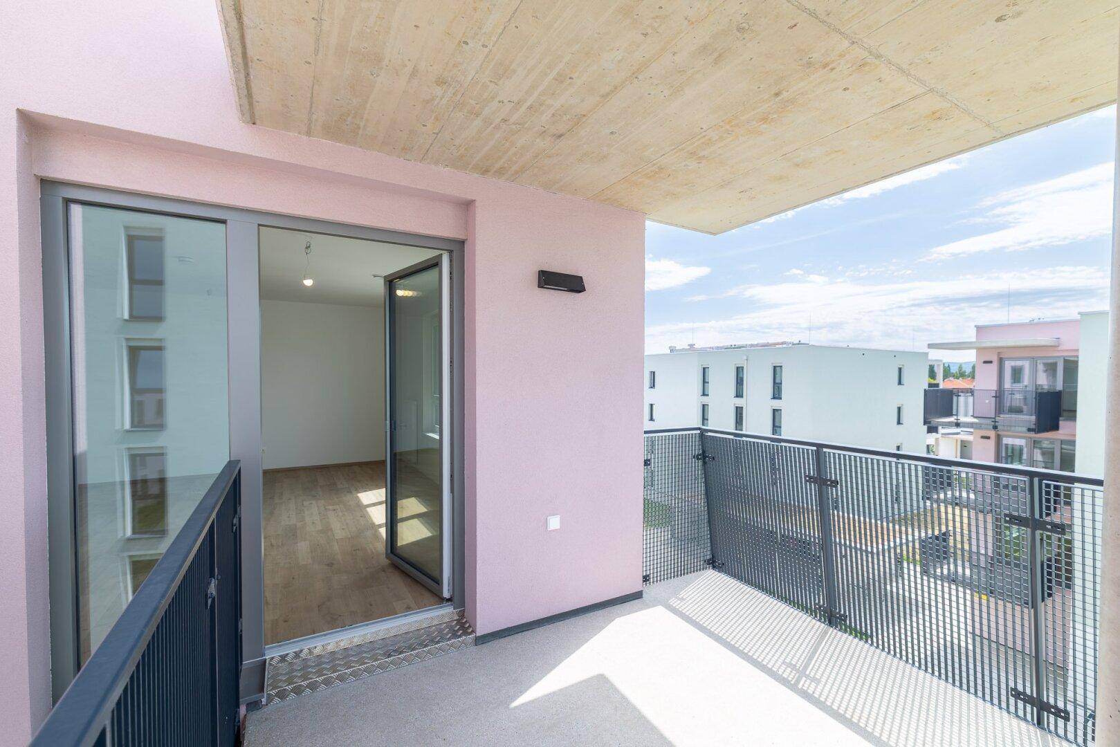 Balkon mit rosafarbener Fassade und Blick auf die umliegenden Wohngebäude.
