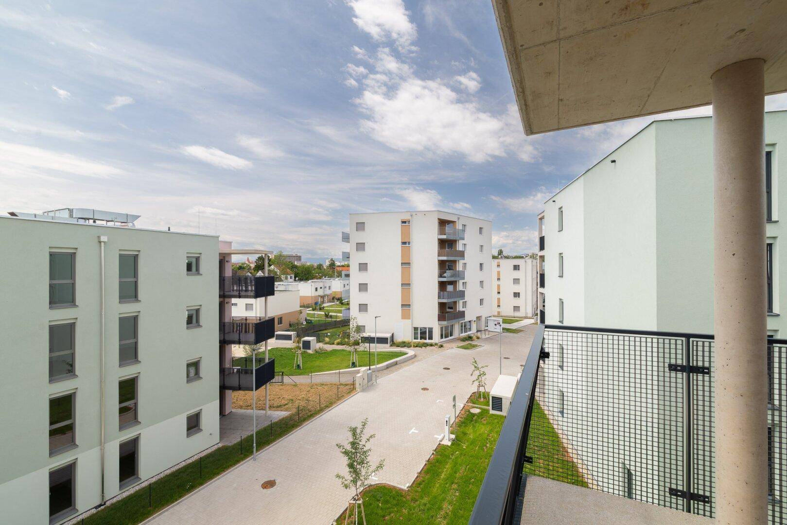 Balkon mit Blick auf die moderne Wohnsiedlung und grüne Außenbereiche.