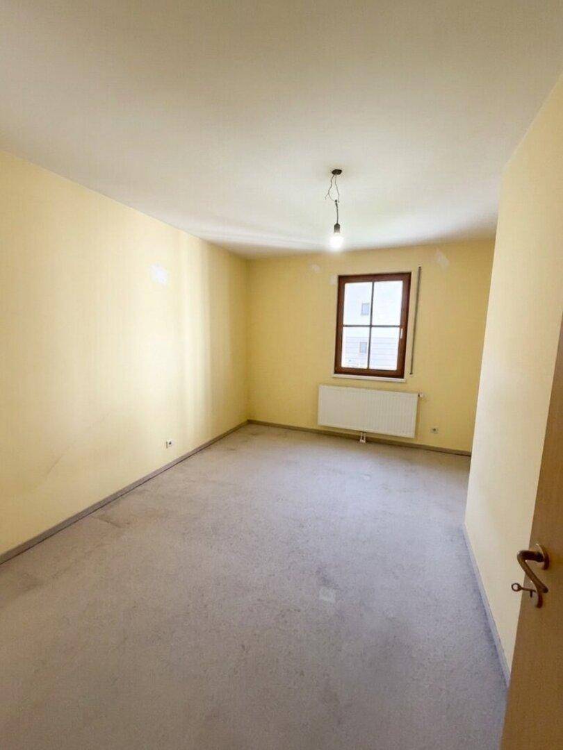 Gemütlicher, leerer Raum mit Teppichboden und gelben Wänden, ideal als Schlafzimmer.