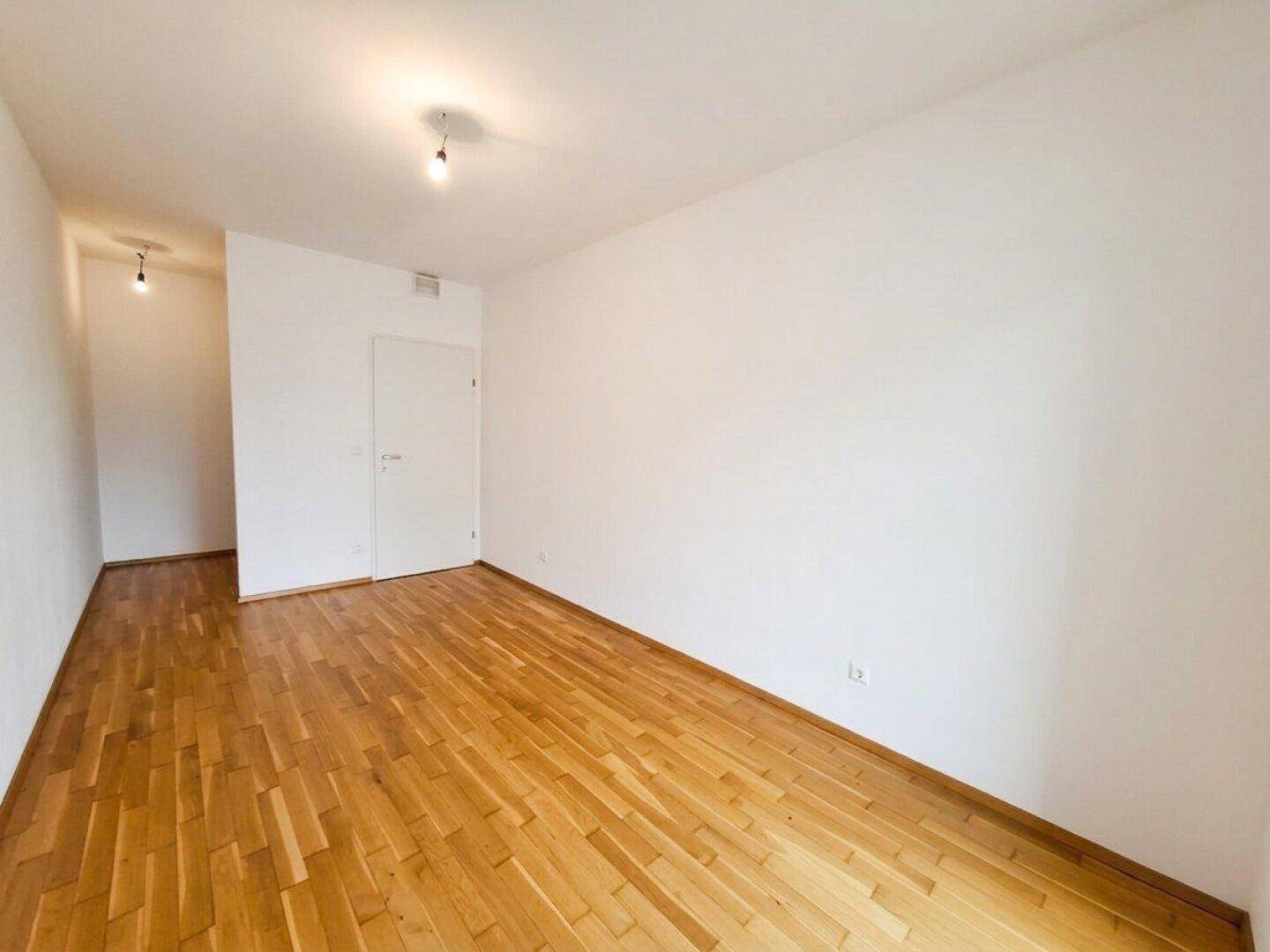 Geräumiges Schlafzimmer mit Parkettboden und zwei Türen, bietet vielseitige Nutzungsmöglichkeiten.