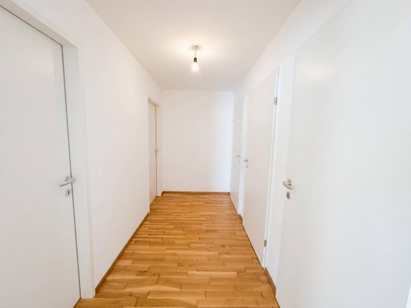 Langer, heller Flur mit Parkettboden und mehreren Türen zu den angrenzenden Zimmern.