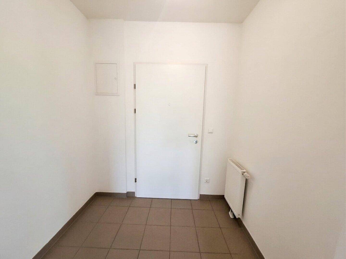 Eingangsbereich mit Fliesenboden und Heizkörper, bietet Zugang zu den Wohnräumen.