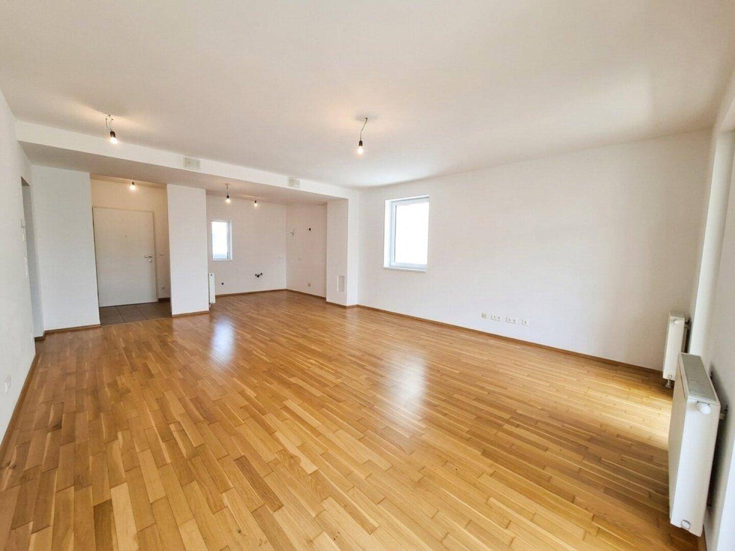 Weitläufiges Zimmer mit Parkettboden und mehreren Türen, ideal für offenes Wohnen.