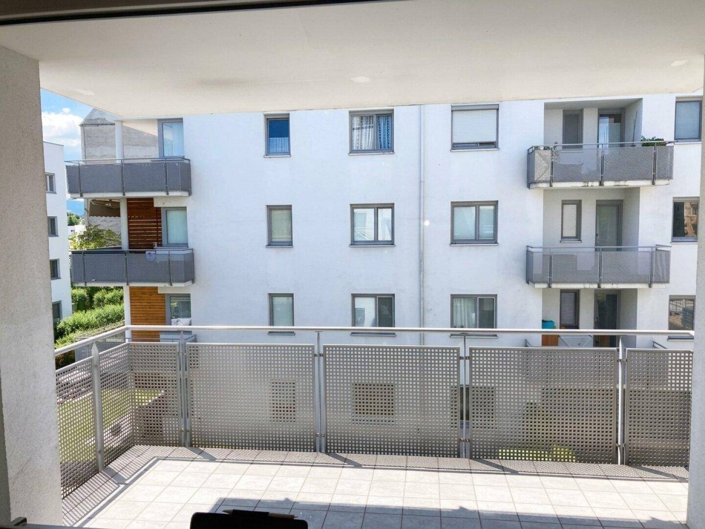 Balkon mit Blick auf die gegenüberliegenden Wohngebäude und deren Balkone, mit viel Tageslicht.