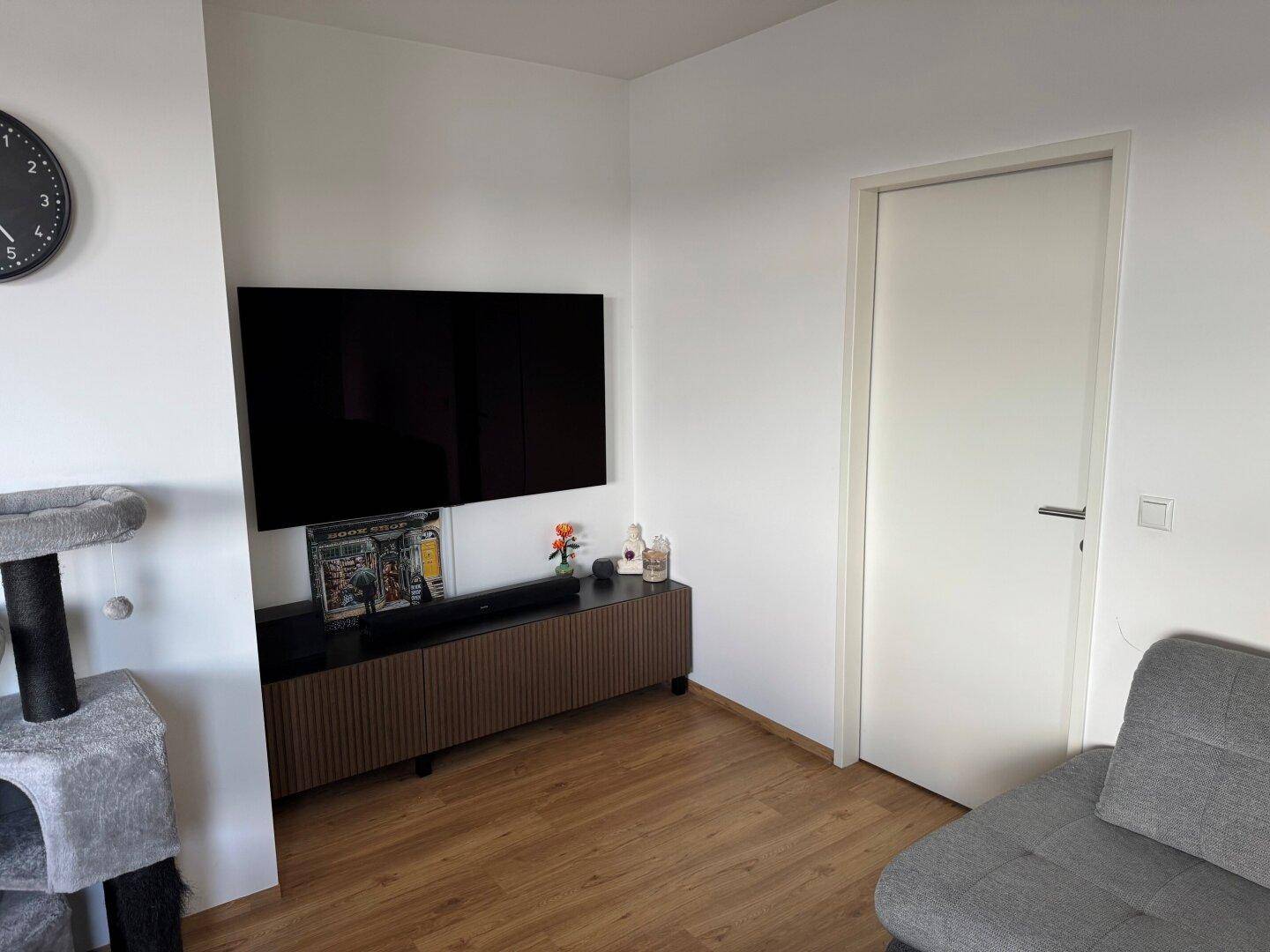 Wohnbereich mit großem Wandfernseher, modernem Medienschrank und einem Katzenbaum.