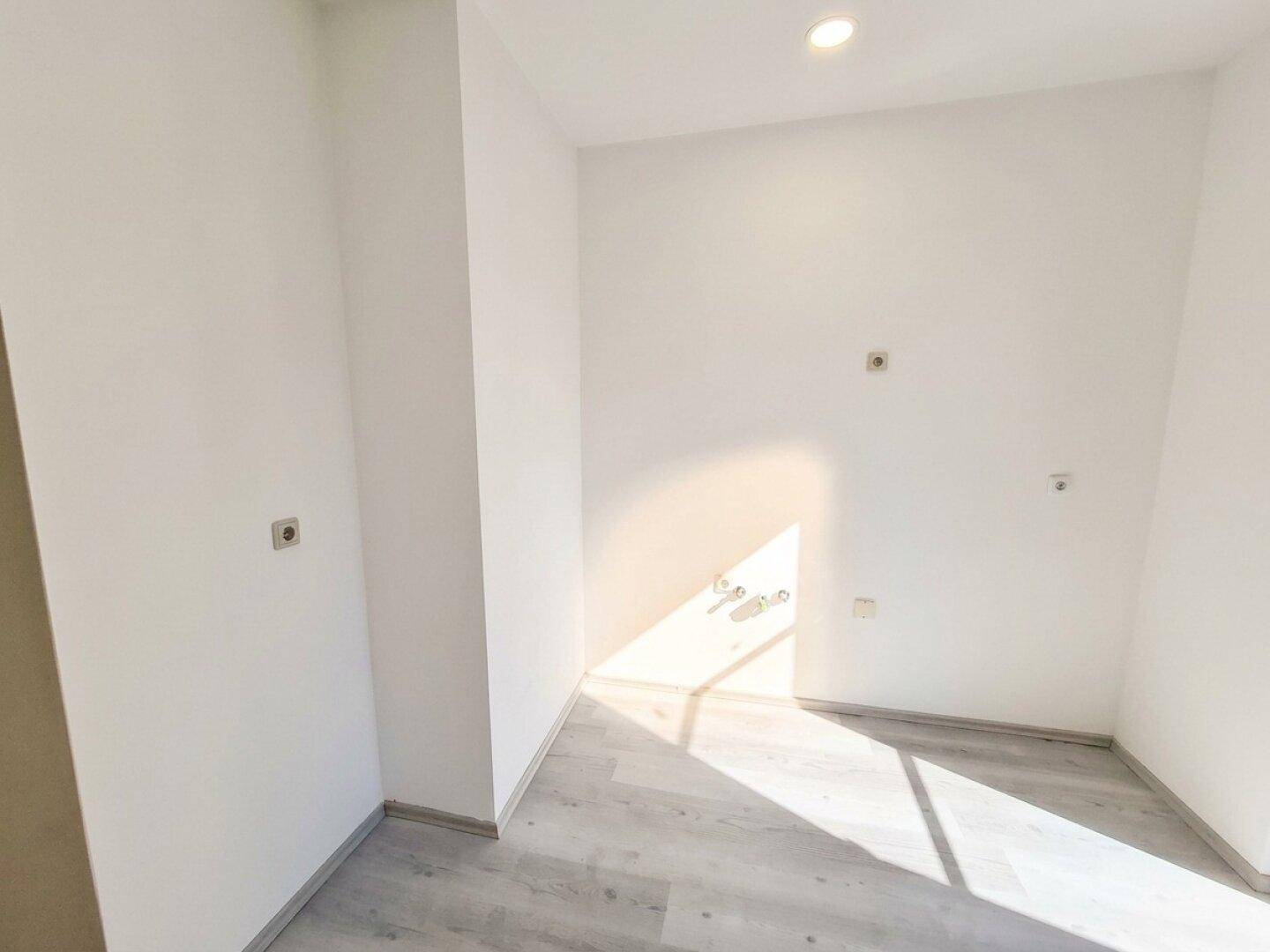 Heller, leerer Raum mit weißen Wänden und hellem Boden, vorbereitet für Installationen.