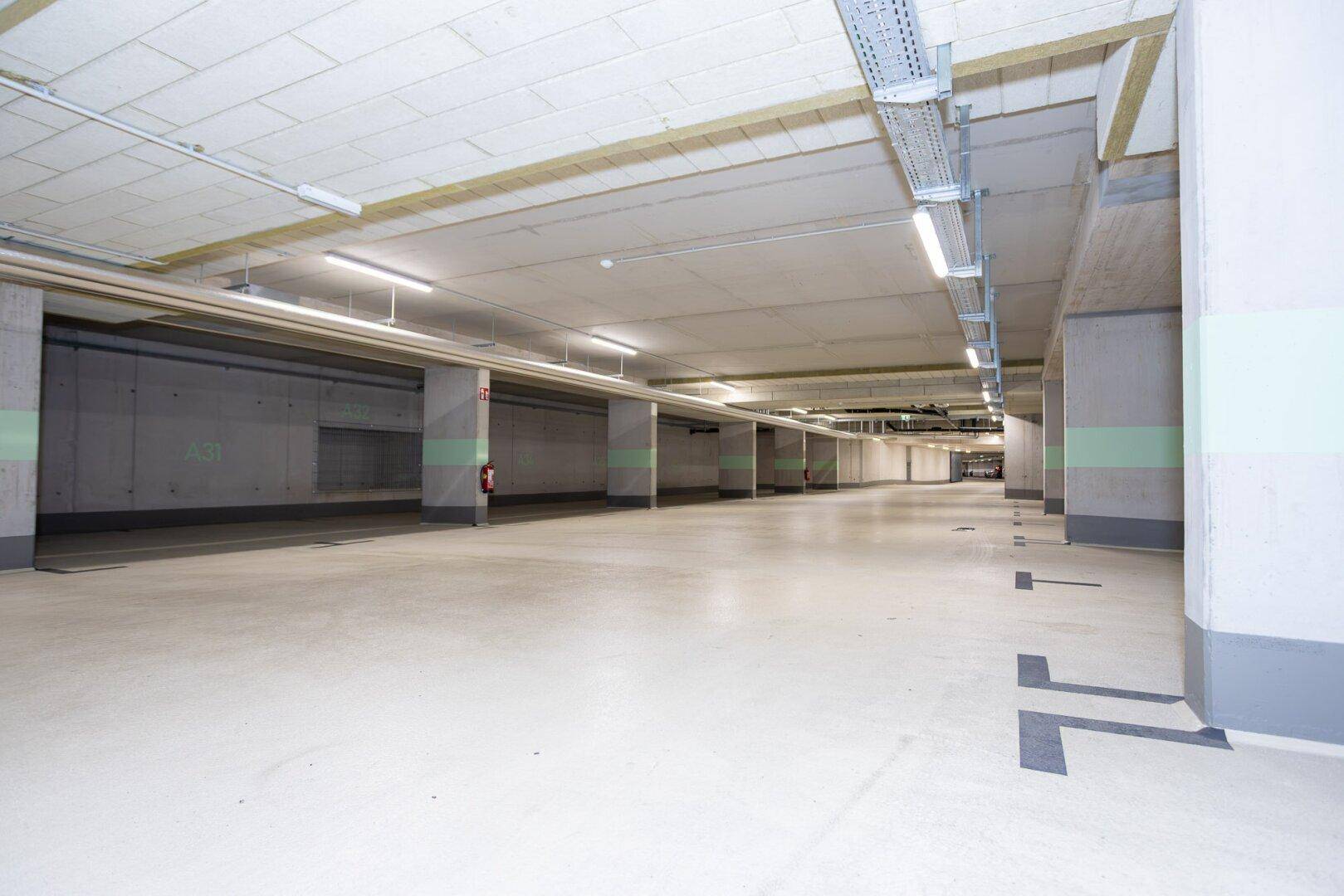 Weitläufige Tiefgarage mit vielen Stellplätzen, Betonpfeilern und klarer Markierung auf dem Boden.