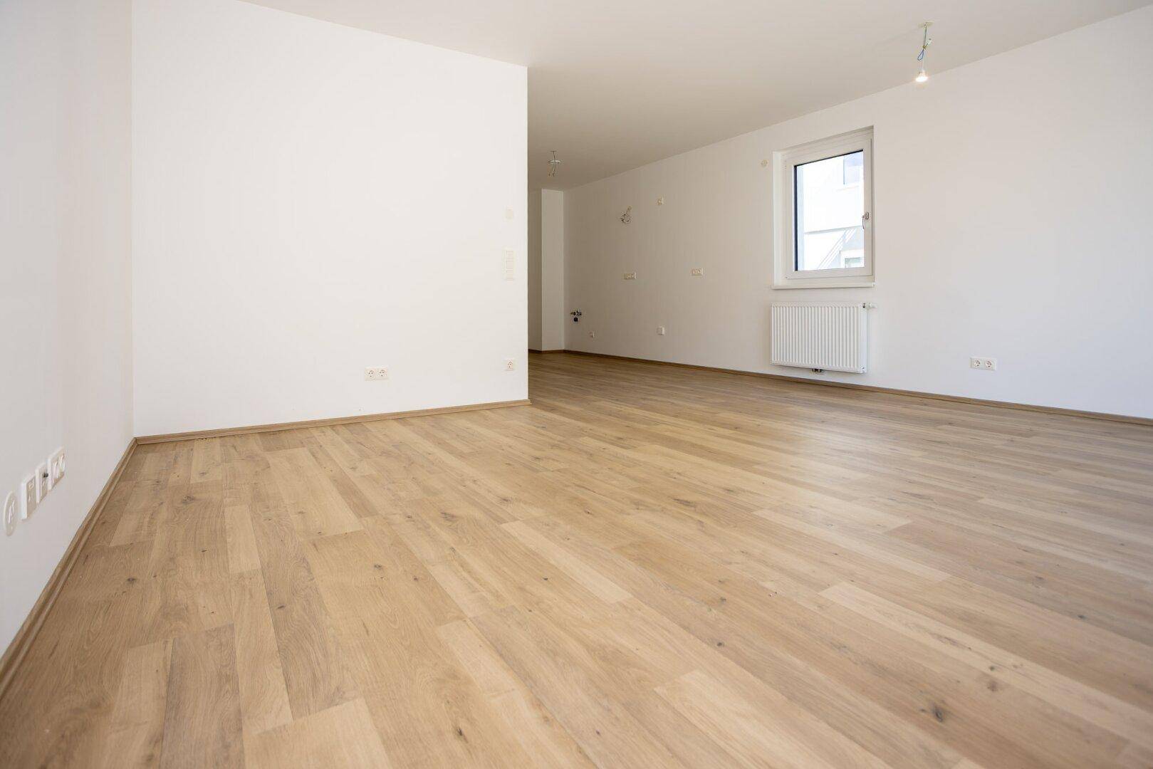 Weiter Blick in den hellen Wohnbereich mit neuem Laminatboden und sauber gestrichenen Wänden.