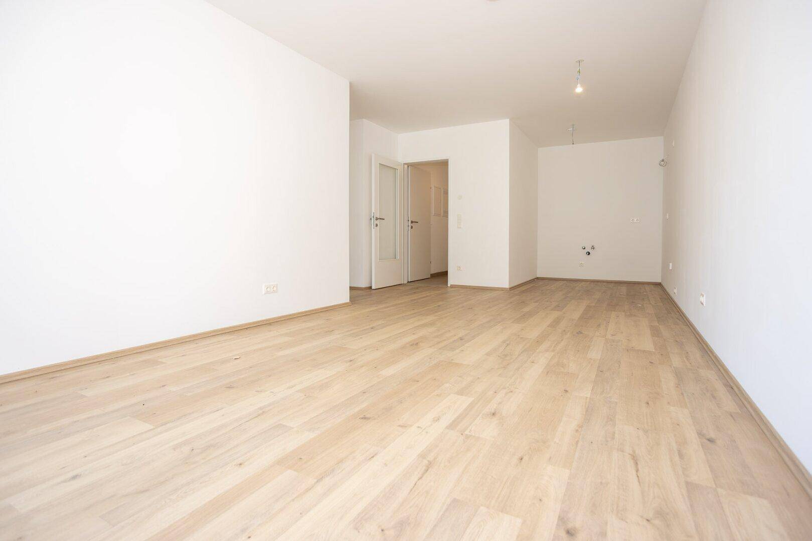 Heller, leerer Raum mit Holzboden und weißen Wänden, bereit für die individuelle Gestaltung.