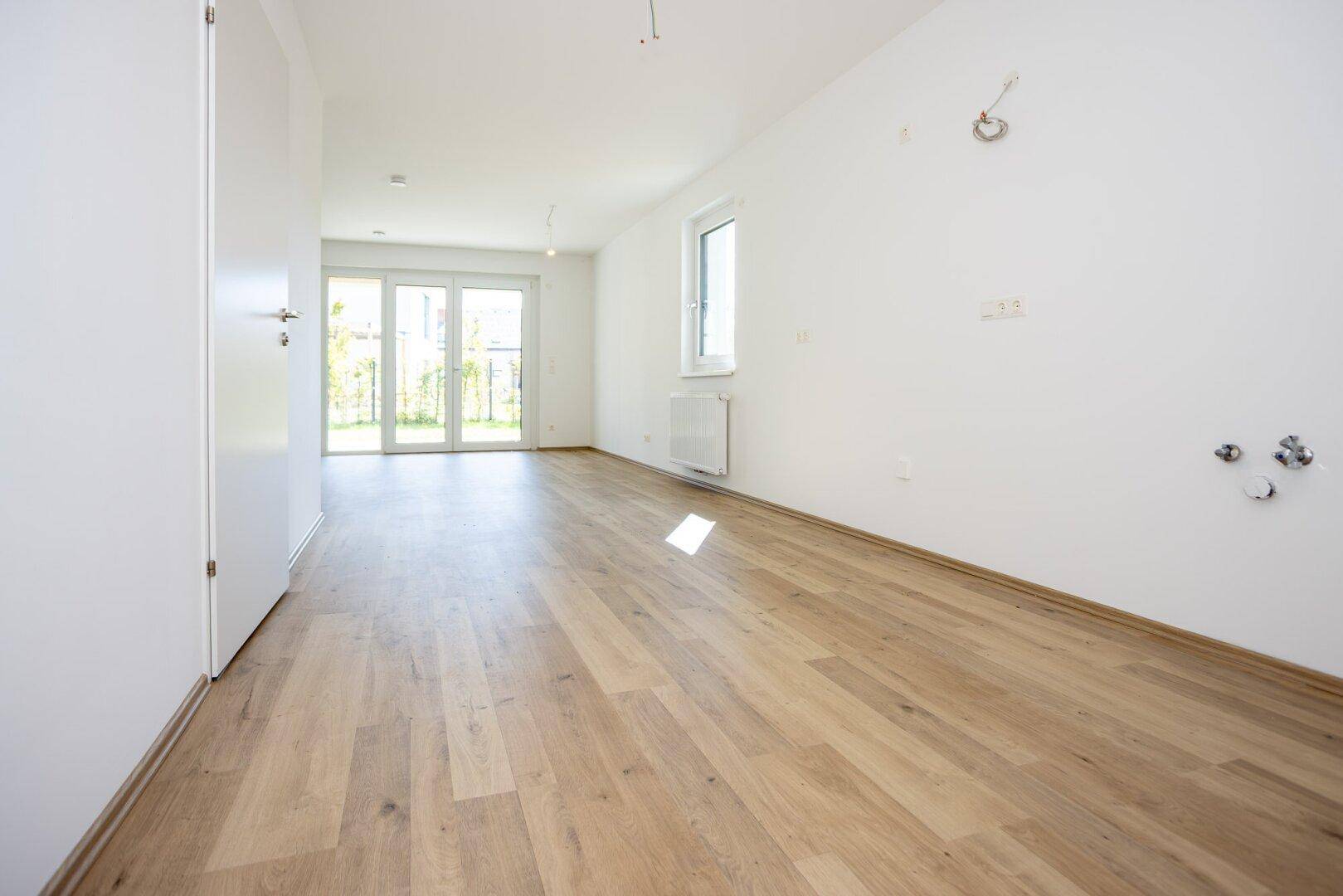 Heller Wohnraum mit modernem Laminatboden und großen Fenstertüren zum Garten.
