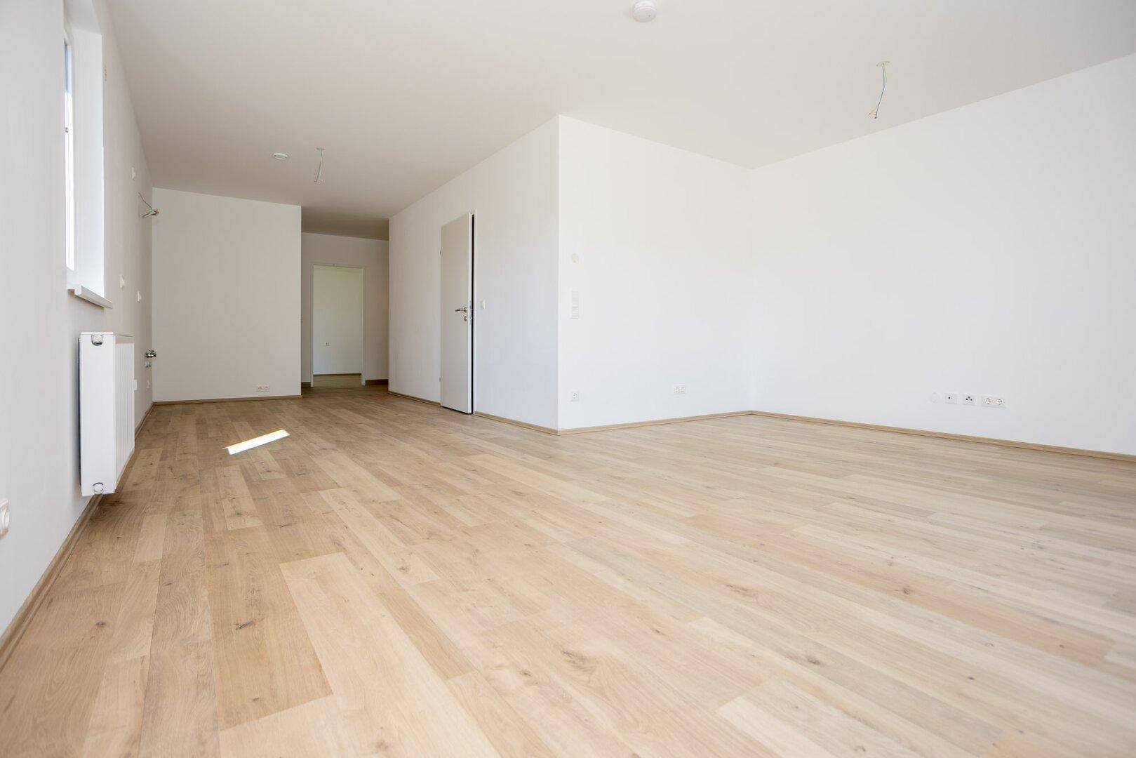 Offener Wohnbereich mit Übergang zum Flur, ausgestattet mit hellem Laminatboden.