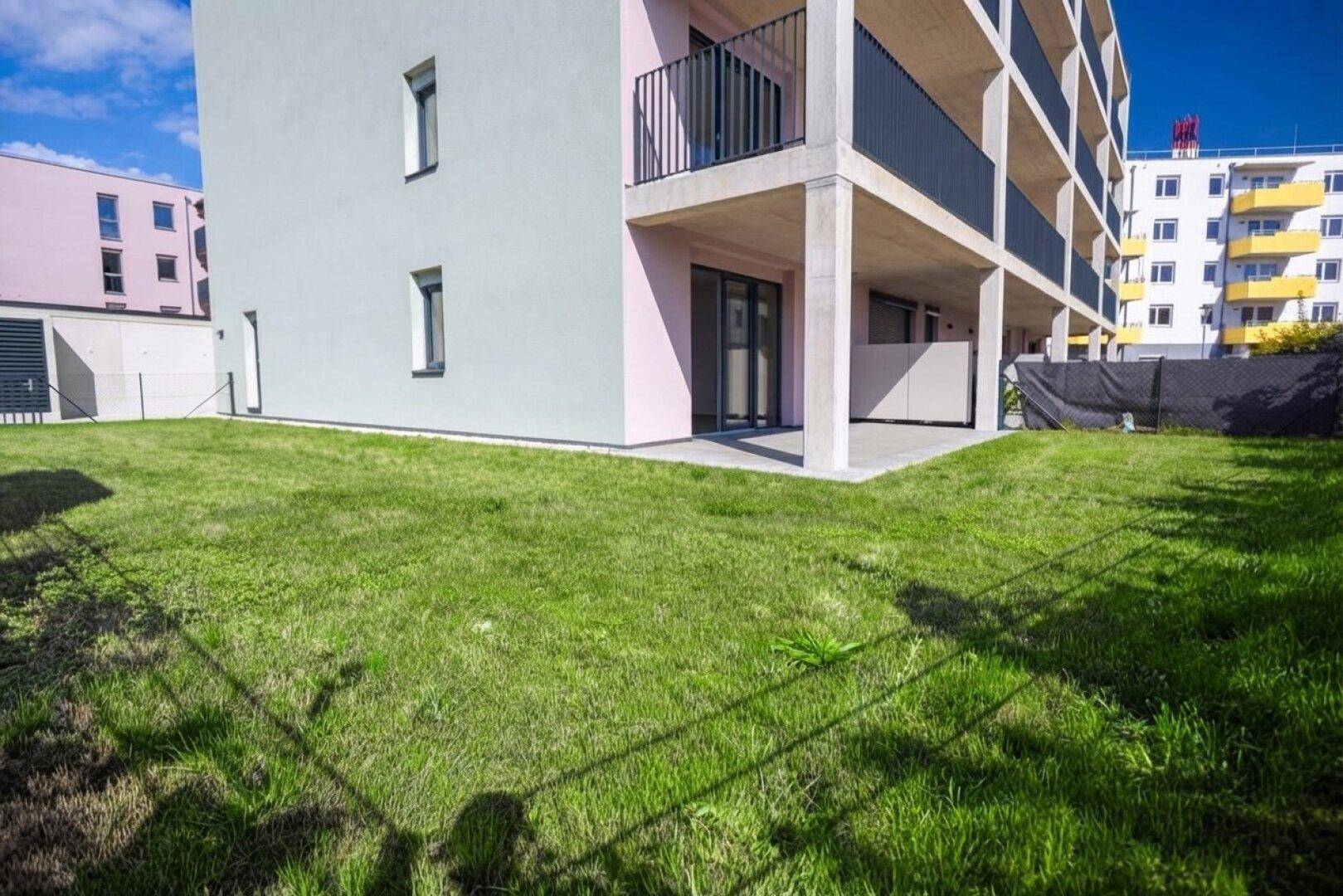 Gepflegte Rasenfläche und private Terrasse im Erdgeschoss einer modernen Wohnanlage.
