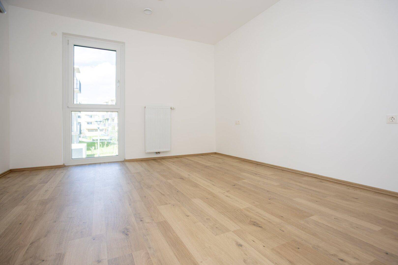 Helles Zimmer mit Laminatboden und weißer Wandgestaltung, ideal als Schlaf- oder Kinderzimmer.